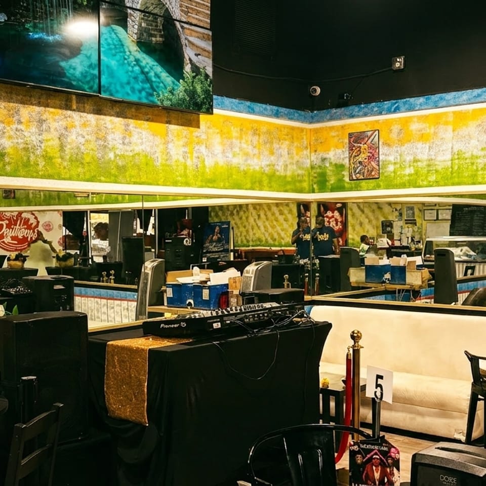 Lounge interior with colorful walls, mirrors, DJ equipment, and seating, including a white couch.